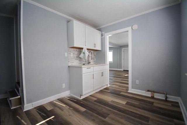 kitchen with sink, white cabinetry, ornamental molding, dark hardwood / wood-style floors, and decorative backsplash