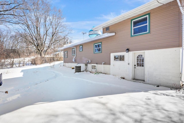 snow covered back of property featuring central air condition unit