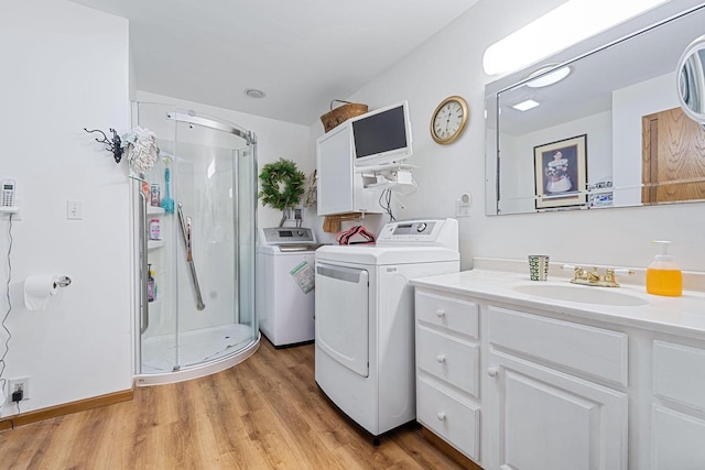 clothes washing area featuring sink, washing machine and dryer, and light hardwood / wood-style flooring