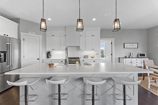 kitchen featuring white cabinetry, high quality fridge, pendant lighting, and a large island with sink