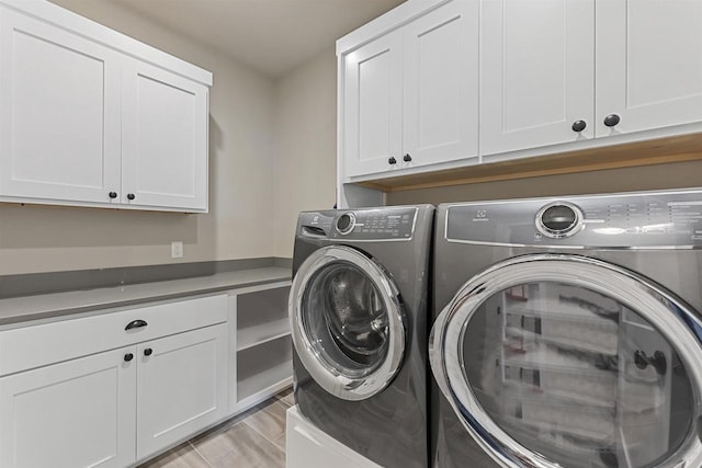 washroom featuring cabinets and washer and clothes dryer