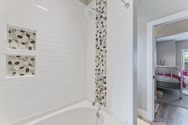 bathroom with hardwood / wood-style flooring and tiled shower / bath