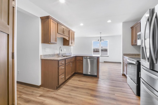 kitchen with appliances with stainless steel finishes, decorative light fixtures, sink, light hardwood / wood-style floors, and kitchen peninsula