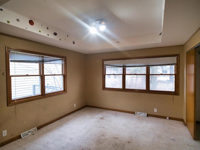 carpeted empty room featuring a tray ceiling