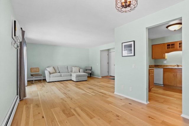 unfurnished living room featuring baseboard heating, sink, and light wood-type flooring