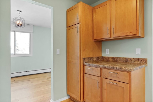 kitchen with hanging light fixtures, a baseboard radiator, and light wood-type flooring