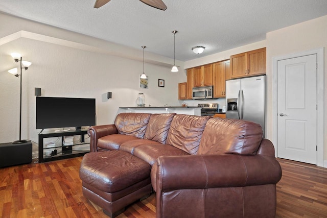 living room with ceiling fan, a textured ceiling, and dark hardwood / wood-style flooring