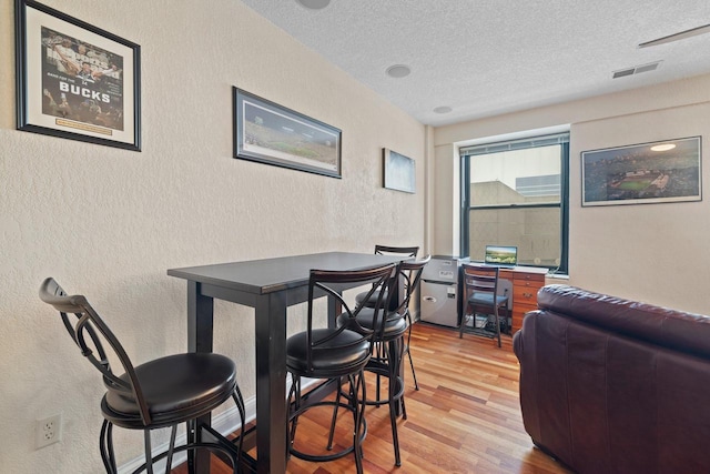 dining area featuring hardwood / wood-style flooring and a textured ceiling