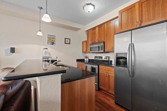 kitchen featuring sink, hanging light fixtures, stainless steel appliances, dark wood-type flooring, and a textured ceiling