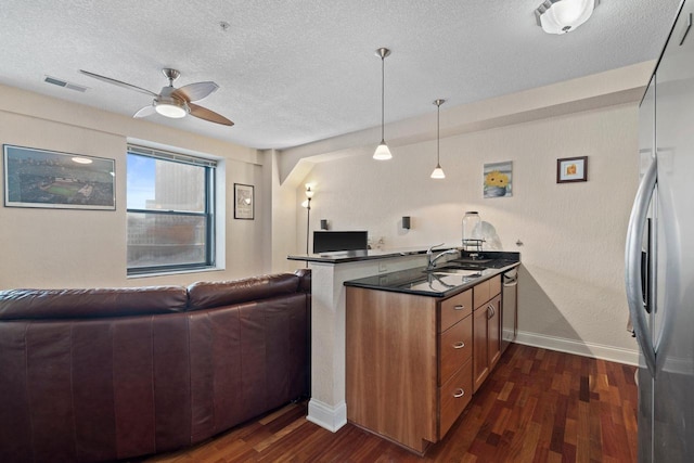 kitchen with dark wood-type flooring, sink, hanging light fixtures, appliances with stainless steel finishes, and kitchen peninsula