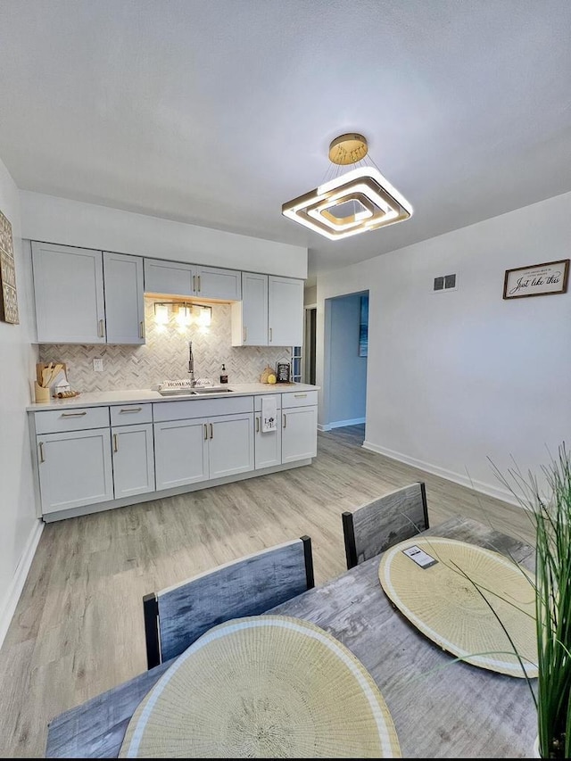 kitchen featuring light wood-type flooring, sink, and backsplash