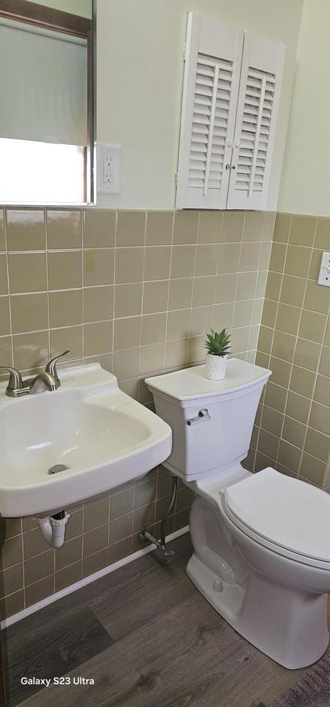 bathroom with hardwood / wood-style flooring, sink, tile walls, and toilet