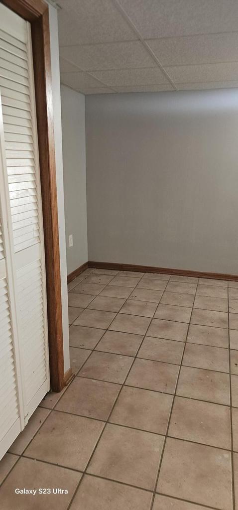 hallway with a drop ceiling and light tile patterned flooring