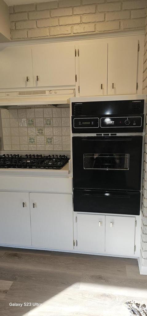 kitchen with white cabinetry, light wood-type flooring, decorative backsplash, and black appliances