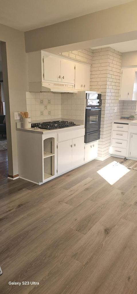 kitchen with dark wood-type flooring, gas cooktop, white cabinetry, tasteful backsplash, and oven