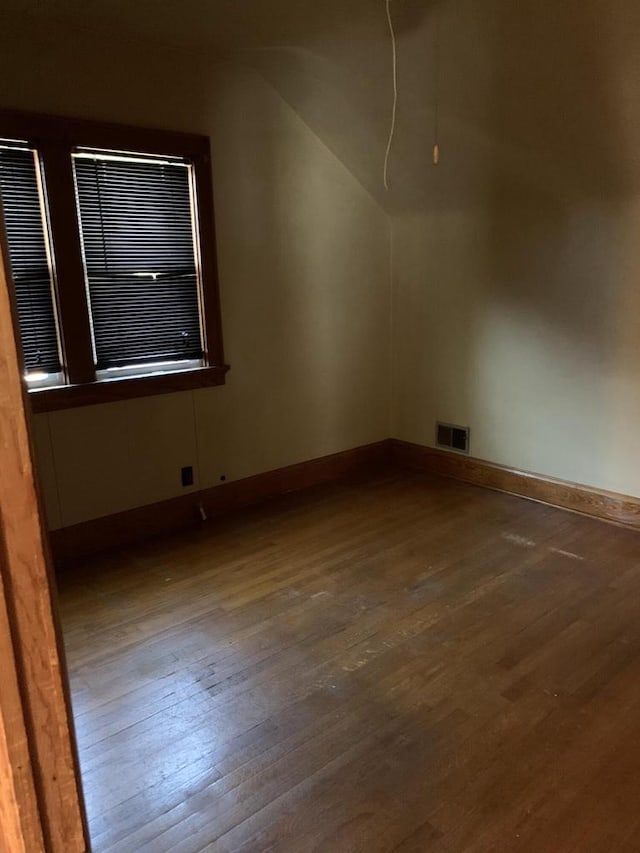 empty room with vaulted ceiling and dark hardwood / wood-style floors