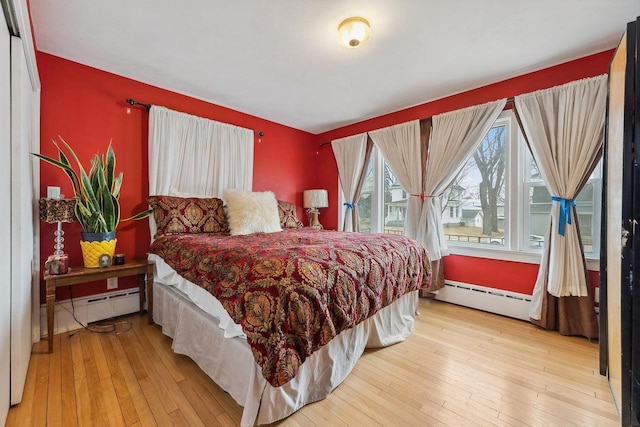 bedroom featuring baseboard heating and light hardwood / wood-style flooring