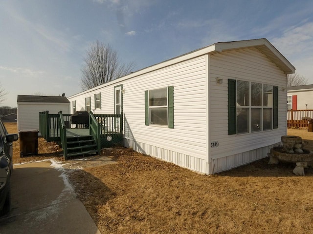 view of property exterior with a wooden deck and a storage unit