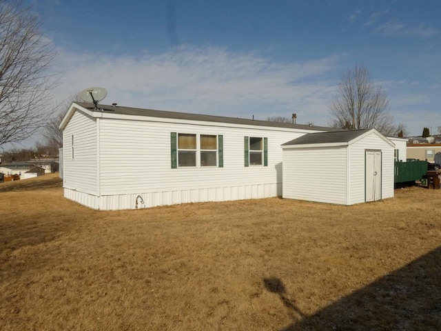 rear view of property featuring a storage shed and a lawn