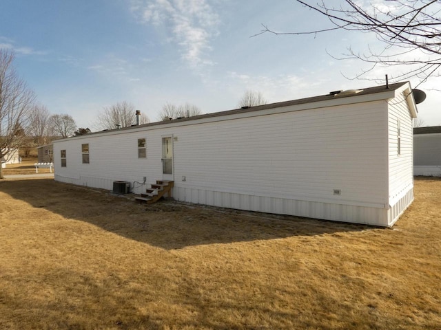 back of property featuring central AC unit and a lawn