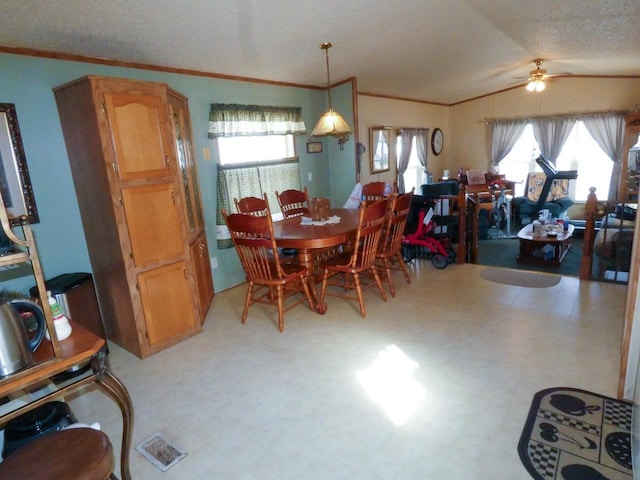 dining space with ceiling fan, lofted ceiling, ornamental molding, and a textured ceiling