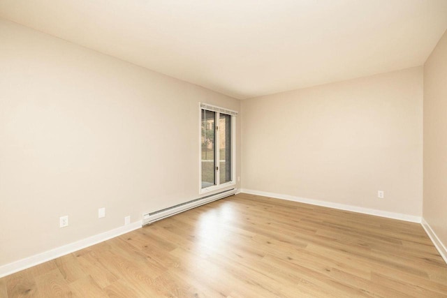 spare room featuring light wood finished floors, a baseboard radiator, and baseboards