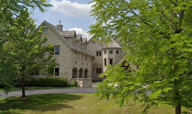 view of front facade with stone siding and a front yard