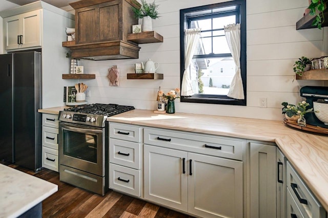 kitchen featuring open shelves, custom range hood, dark wood-type flooring, freestanding refrigerator, and stainless steel gas range oven