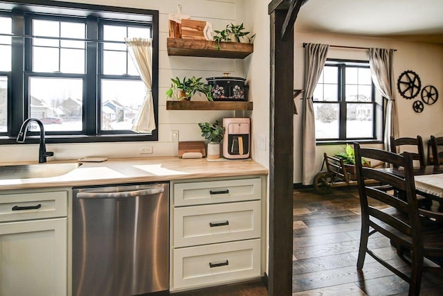 kitchen featuring a sink, light countertops, stainless steel dishwasher, open shelves, and dark wood finished floors