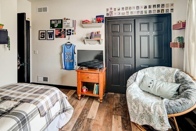 bedroom featuring a closet, visible vents, baseboards, and wood finished floors