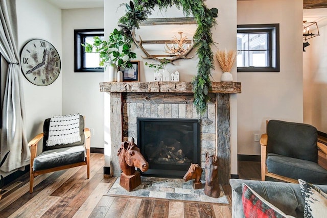 living area featuring a wealth of natural light, wood finished floors, and a glass covered fireplace