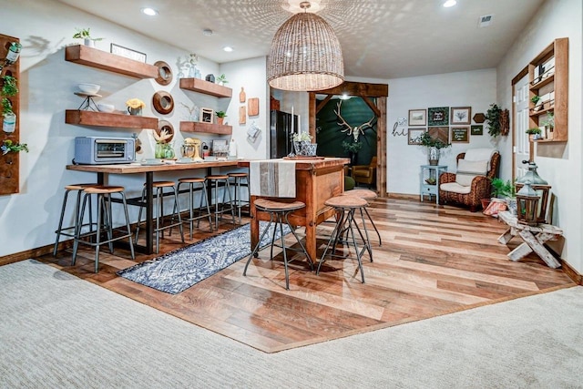 dining room with recessed lighting, a toaster, wood finished floors, visible vents, and baseboards