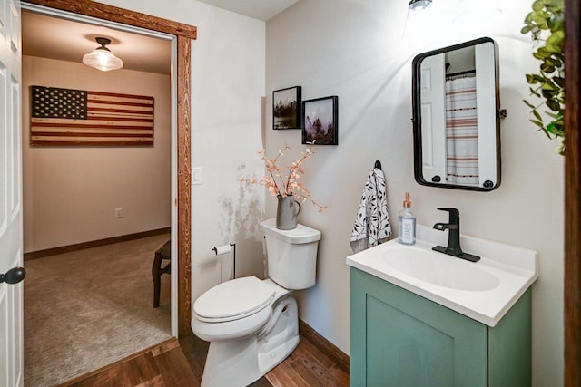 bathroom featuring baseboards, vanity, toilet, and wood finished floors