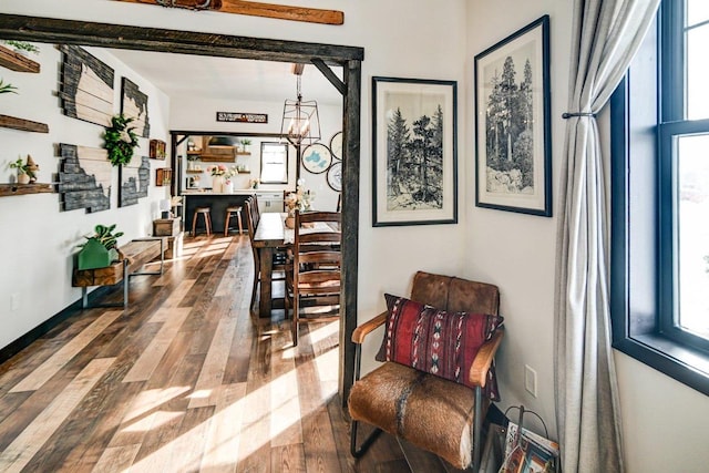 hall featuring baseboards, an inviting chandelier, and wood finished floors