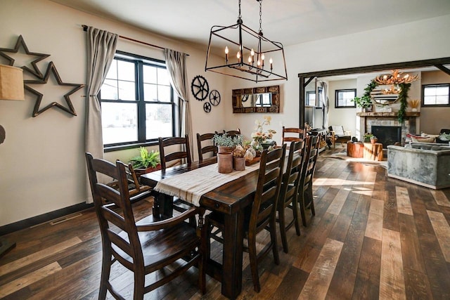 dining area featuring dark wood-style flooring, a fireplace, and baseboards