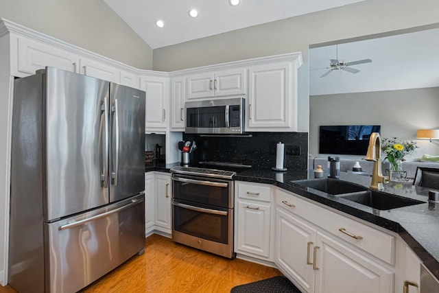 kitchen featuring vaulted ceiling, white cabinetry, appliances with stainless steel finishes, and sink