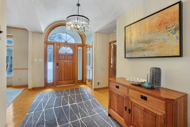 foyer entrance featuring lofted ceiling, a chandelier, and light wood-type flooring