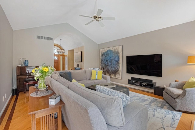 living room featuring lofted ceiling, ceiling fan with notable chandelier, and light wood-type flooring