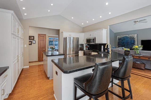 kitchen featuring sink, a breakfast bar, appliances with stainless steel finishes, white cabinets, and kitchen peninsula