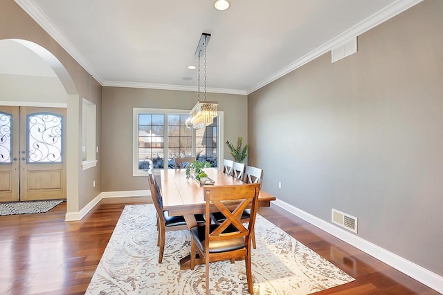 dining space with crown molding, dark wood-type flooring, french doors, and a chandelier