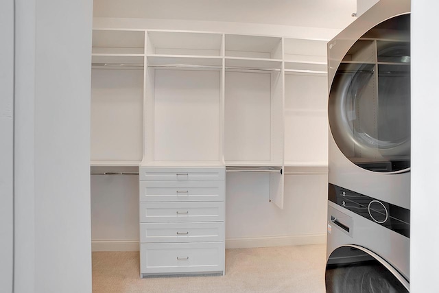 walk in closet with stacked washer / drying machine and light carpet