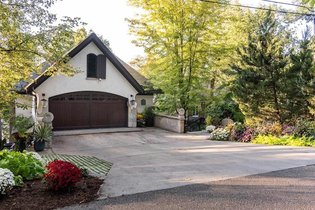 view of side of home with concrete driveway, a garage, and stucco siding