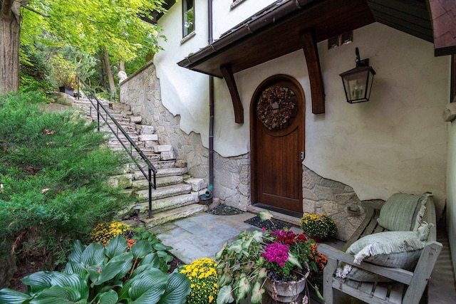 doorway to property featuring stone siding and stucco siding