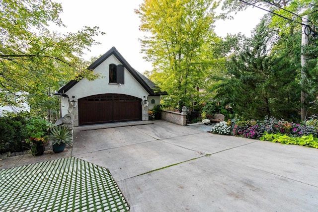 exterior space with stone siding, stucco siding, driveway, and a garage