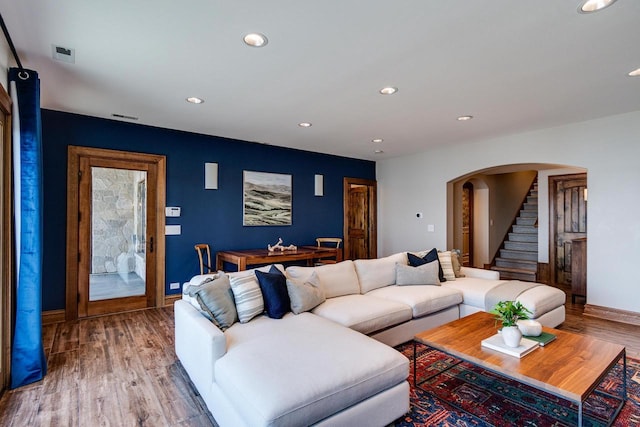 living room featuring wood finished floors, recessed lighting, stairway, arched walkways, and baseboards