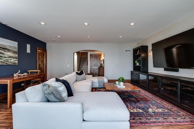 living area featuring baseboards, stairway, recessed lighting, wood finished floors, and arched walkways