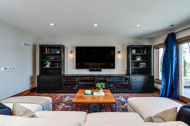 living room with recessed lighting, built in features, wood finished floors, and visible vents