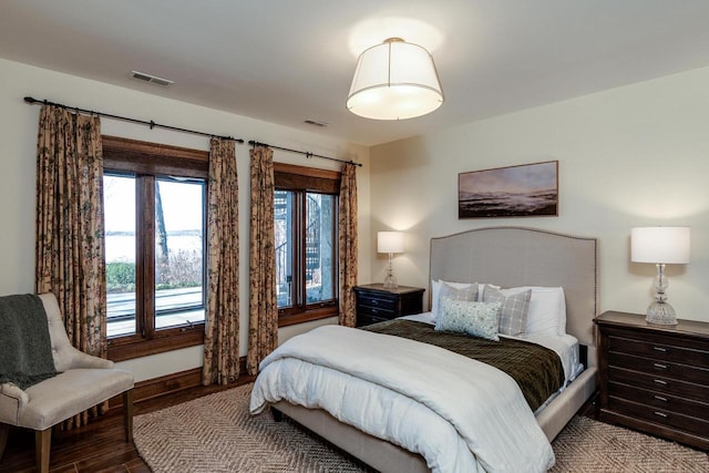 bedroom with visible vents, baseboards, and wood finished floors