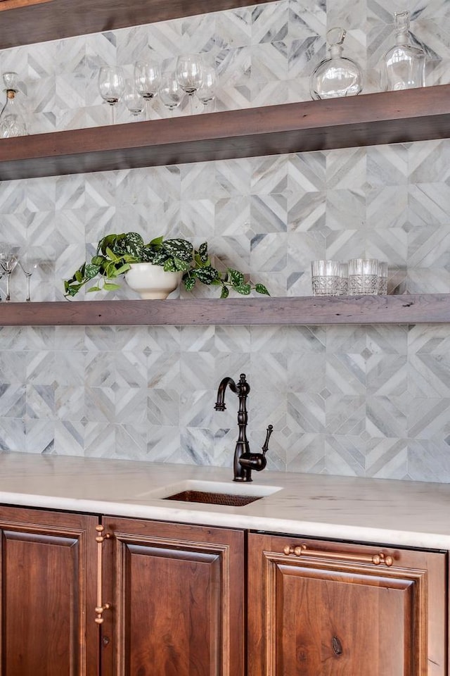 bar featuring decorative backsplash, bar area, and a sink