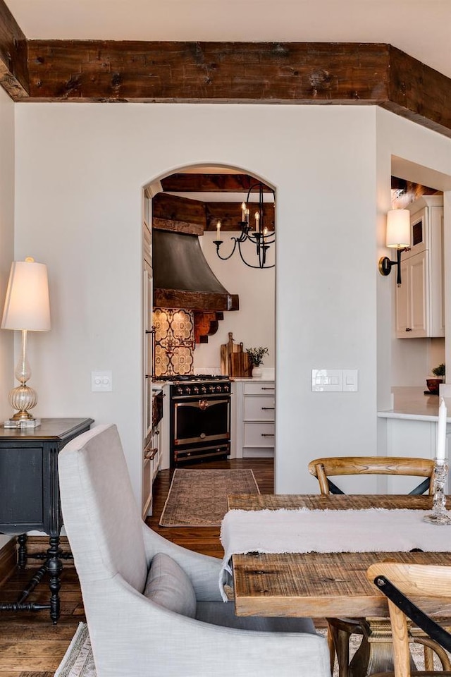 living area with dark wood-style floors, an inviting chandelier, beam ceiling, a fireplace, and arched walkways